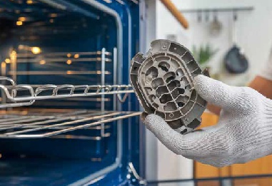 a gloved hand pulls a replacement part from a conventional home oven